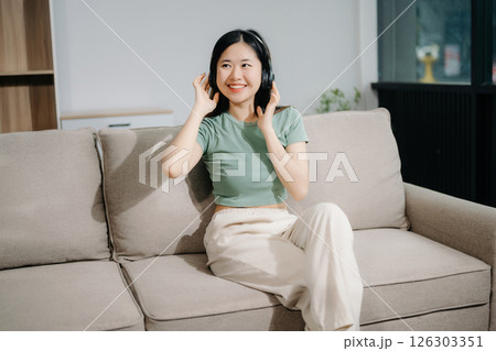Young asian woman relax on comfortable couch at home texting messaging on smartphone and tablet smiling girl use cellphone  shopping online 126303351