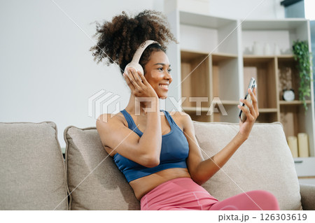 Active woman in athleisure sitting on yoga mat with tablet, headphones and modern home lifestyle. 126303619