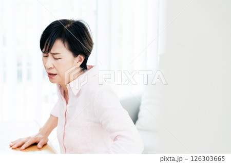 リビングで腰痛に苦しむ中高年女性 リビングで腰痛に苦しむ中高年女性 126303665