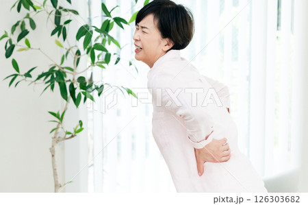 リビングで腰痛に苦しむ中高年女性 リビングで腰痛に苦しむ中高年女性 126303682
