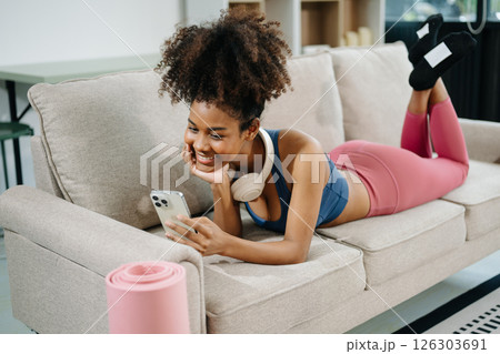 Active woman in athleisure sitting on yoga mat with tablet, headphones and modern home lifestyle. 126303691