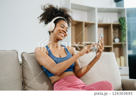 Active woman in athleisure sitting on yoga mat with tablet, headphones and modern home lifestyle. Active woman in athleisure sitting on yoga mat with tablet, headphones and modern home lifestyle. 126303693