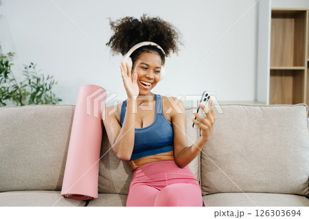 Active woman in athleisure sitting on yoga mat with tablet, headphones and modern home lifestyle. 126303694