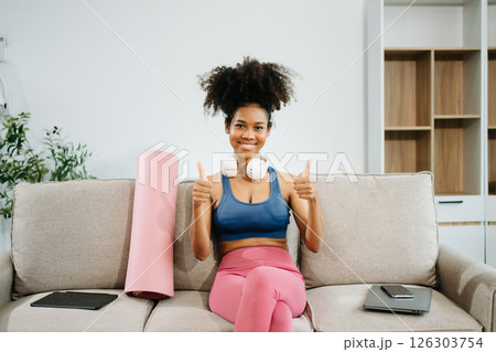 Active woman in athleisure sitting on yoga mat with tablet, headphones and modern home lifestyle. Active woman in athleisure sitting on yoga mat with tablet, headphones and modern home lifestyle. 126303754