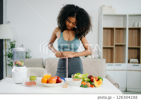 Smiling woman measuring waist, holding green apple with fruits, veggies, Smiling woman measuring waist, holding green apple with fruits, veggies, 126304288