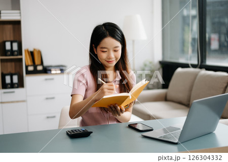 Female students note from the books at the Asian girl library sitting at the desk using laptop computer and tablet 126304332