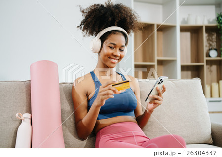 Active woman in athleisure sitting on yoga mat with tablet, headphones and modern home lifestyle. 126304337