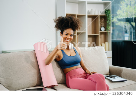 Active woman in athleisure sitting on yoga mat with tablet, headphones and modern home lifestyle. 126304340
