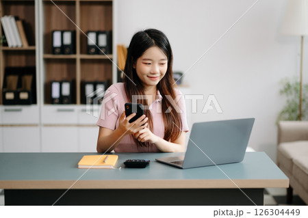 Asian woman sitting at a desk using a laptop computer Navigating Finance and Marketing with Technology Asian woman sitting at a desk using a laptop computer Navigating Finance and Marketing with Technology 126304449