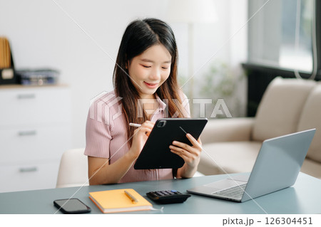 Asian woman sitting at a desk using a laptop computer Navigating Finance and Marketing with Technology 126304451