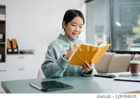 Young smiling woman wearing headphones and talking into a microphone at the radio station, entertainment a live podcast for their channel, communication 126304928