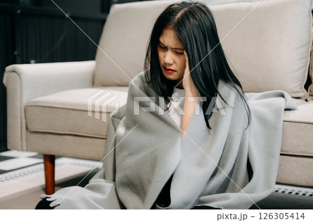 Young Asian woman suffering from flu symptoms, covered with a blanket on a sofa. Concept of illness, healthcare, 126305414