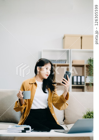 Young asian woman relax on comfortable couch at home texting messaging on smartphone and tablet smiling girl use cellphone Young asian woman relax on comfortable couch at home texting messaging on smartphone and tablet smiling girl use cellphone 126305599