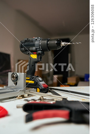 Electric cordless drill with bits and hand tools on workbench in workshop. Home renovation, construction and repair concept Electric cordless drill with bits and hand tools on workbench in workshop. Home renovation, construction and repair concept 126306088