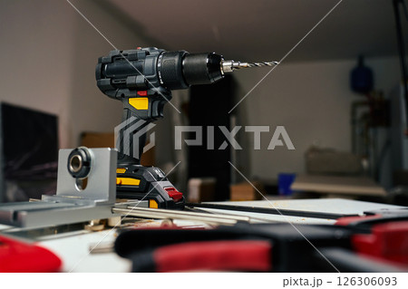 Electric cordless drill with bits and hand tools on workbench in workshop. Home renovation, construction and repair concept 126306093