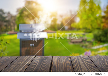 summer time in backyard garden with grill BBQ, wooden table, blurred background summer time in backyard garden with grill BBQ, wooden table, blurred background 126306863