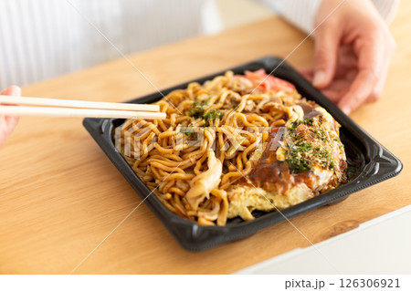 会社のデスクで焼きそばお好み焼きランチを食べるミドル女性 会社のデスクで焼きそばお好み焼きランチを食べるミドル女性 126306921