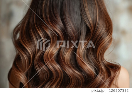 Dark brown hair with flowing copper streaks in soft waves, viewed from behind against a neutral wall 126307552