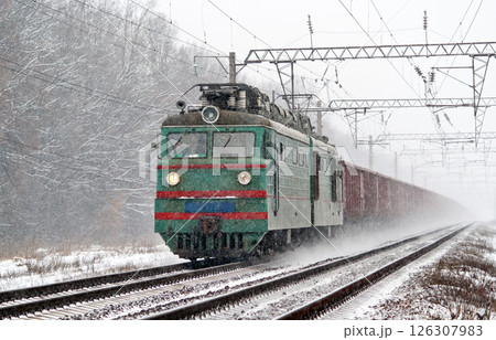 Electric freight train is moving in a snowstorm 126307983