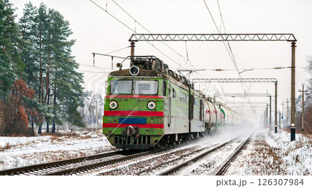 Old Soviet electric locomotive with a heavy freight train in winter in Kyiv Oblast of Ukraine 126307984