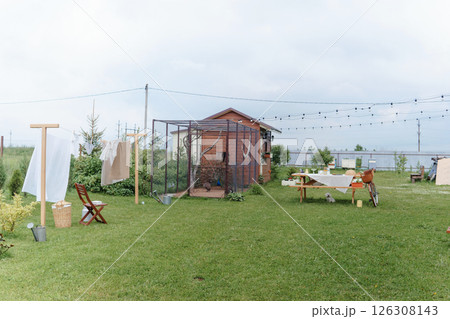 Backyard scene with clothesline, peacock aviary, picnic table, and bike, representing serene countryside life and farm activities. 126308143