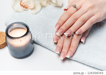 Woman showing french manicure on towel with candle and orchid flower Woman showing french manicure on towel with candle and orchid flower 126308343