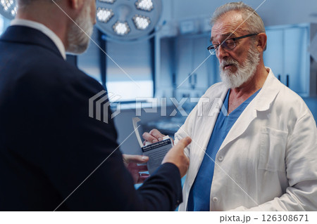 Medical sales representative introducing pharmaceutical products to doctor. Hospital setting. Medical sales representative introducing pharmaceutical products to doctor. Hospital setting. 126308671