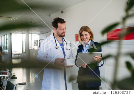 Confident female medical sales representative introducing pharmaceutical products to doctor. Confident female medical sales representative introducing pharmaceutical products to doctor. 126308727