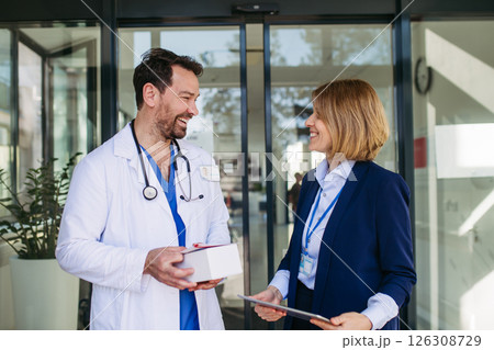 Female medical sales representative presenting medication to doctor Female medical sales representative presenting medication to doctor 126308729