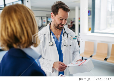 Female medical sales representative presenting medication to doctor Female medical sales representative presenting medication to doctor 126308737