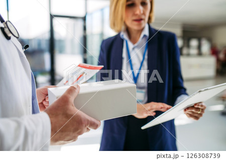 Female medical sales representative presenting medication to doctor 126308739