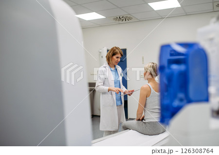Doctor explaining results from CT scan to patient in diagnostic imaging room 126308764