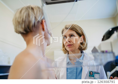 Healthcare professional adjusts the patient for accurate breast imaging. Healthcare professional adjusts the patient for accurate breast imaging. 126308791