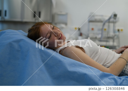 Teenage girl waiting for medical examination, lying on hospital bed. 126308846