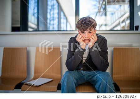 Teenage boy waiting alone in hospital waiting area before medical checkup. 126308927
