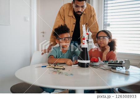 Father teaching kids about STEM, robotics, and discussing technology. 126308933