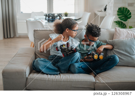 Siblings building robotic car at home as part of STEM learning. 126308967
