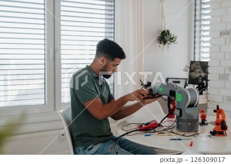Young engineer building and programming a robotic arm at home. Young engineer building and programming a robotic arm at home. 126309017