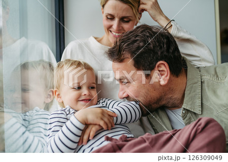 Parents playing with little son, sitting by window. Parents playing with little son, sitting by window. 126309049