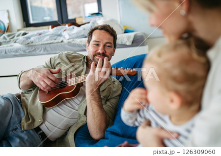 Family bonding moment. Father playing guitar for his family. 126309060