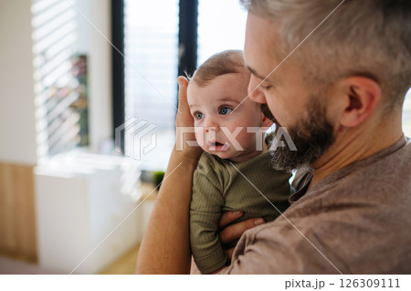 Portrait of father holding baby son in arms. 126309111