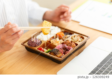 会社のデスクで和食の幕の内弁当を食べるミドル女性 会社のデスクで和食の幕の内弁当を食べるミドル女性 126309249