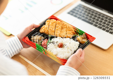 会社のデスクでトンカツ弁当を食べるミドル女性 会社のデスクでトンカツ弁当を食べるミドル女性 126309331