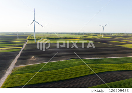 Agricultural tractor is working on the field with wind turbines. Aerial view 126309488