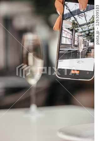 smartphone capturing champagne glass in modern cafe interior smartphone capturing champagne glass in modern cafe interior 126309583