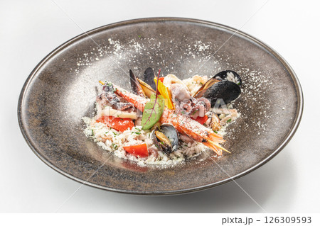 Gourmet seafood risotto with shellfish and grated cheese on an elegant ceramic plate. Gourmet seafood risotto with shellfish and grated cheese on an elegant ceramic plate. 126309593