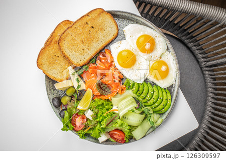 Healthy breakfast plate with eggs, smoked salmon, avocado, toast, and fresh salad. Delicious balanced food concept. top view 126309597