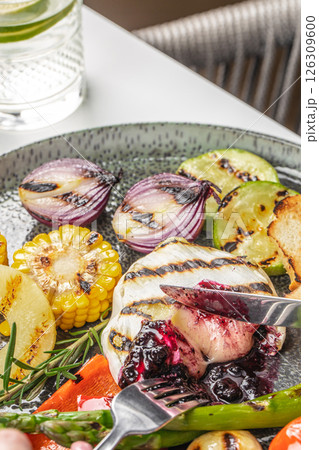 Grilled vegetables and melted cheese with berry sauce on a plate. Grilled brie or camembert with jam Grilled vegetables and melted cheese with berry sauce on a plate. Grilled brie or camembert with jam 126309600