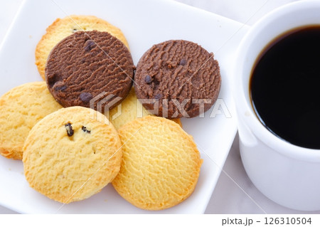 白いお皿に盛ったおいしそうなクッキーと、淹れたての香ばしいコーヒーで、コーヒーブレイクの幸せな時間 白いお皿に盛ったおいしそうなクッキーと、淹れたての香ばしいコーヒーで、コーヒーブレイクの幸せな時間 126310504