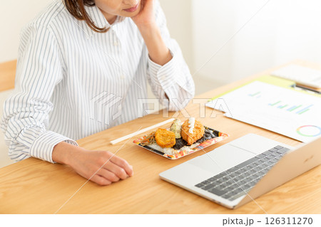 会社のデスクで海苔弁当を前に食欲不振に苦しむミドル女性 126311270